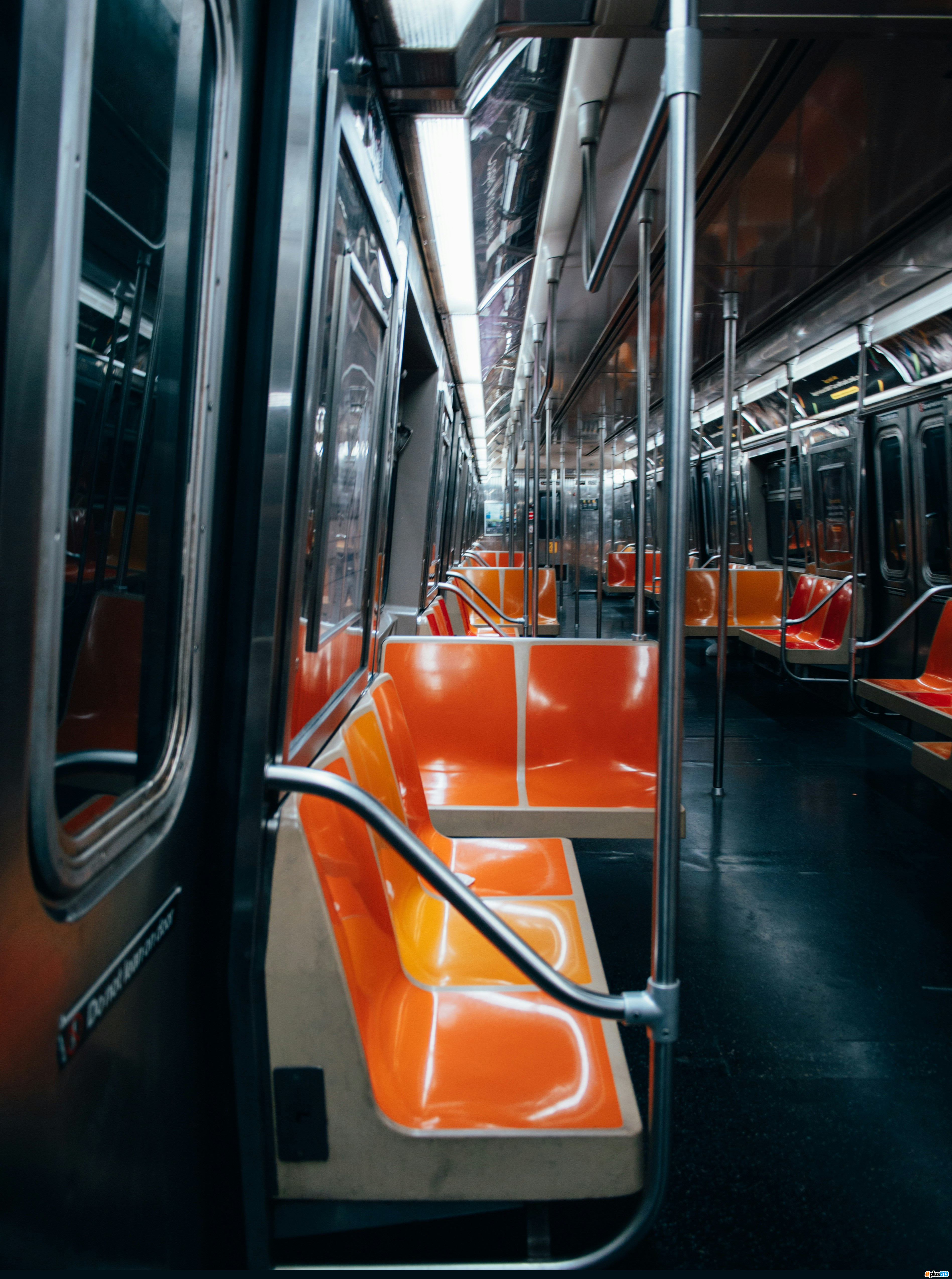 Empty orange plastic seats inside a brightly lit subway car by Dongsh