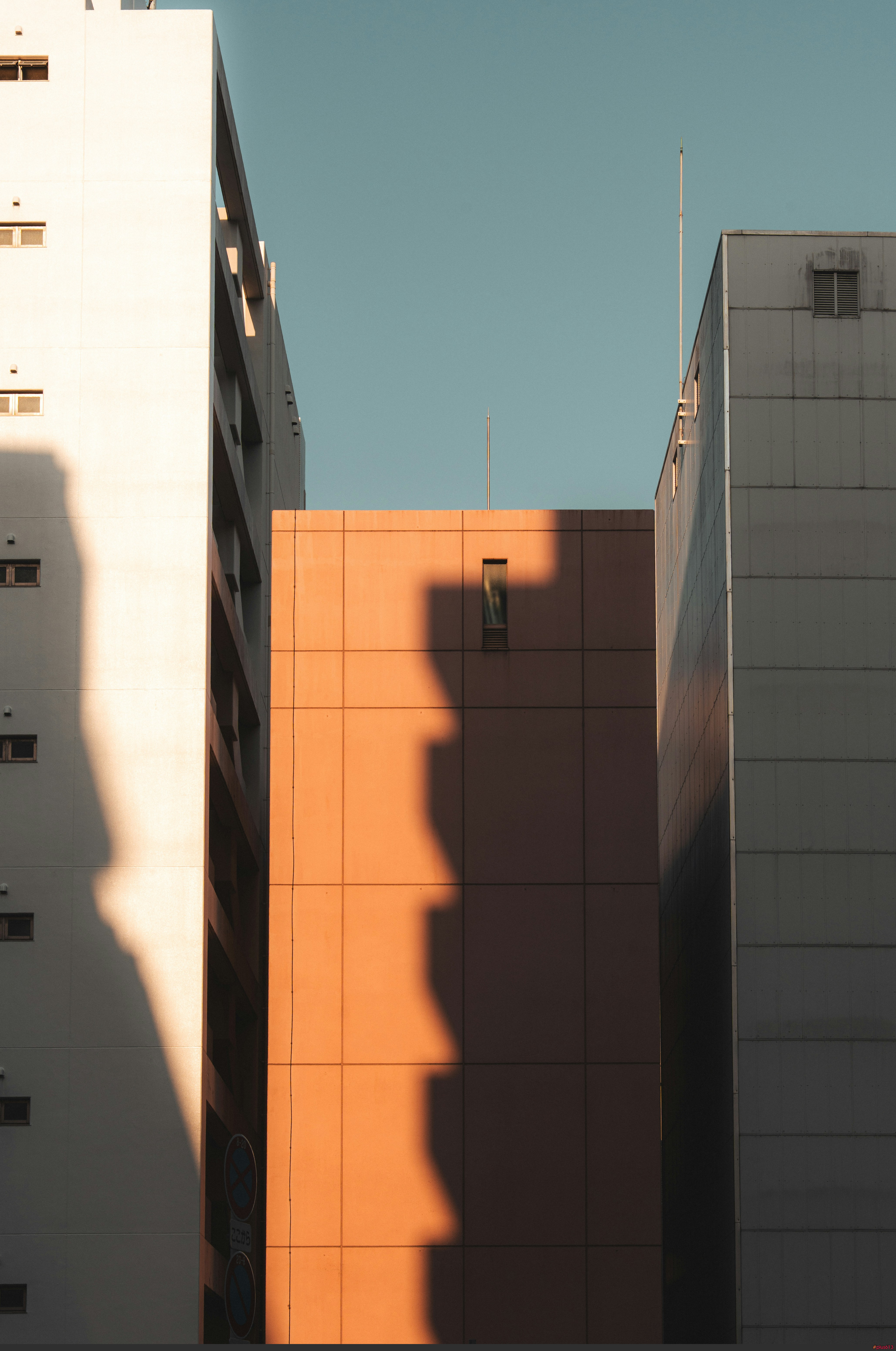 Tall buildings with strong shadows under a clear blue sky by Alexander Kaufmann