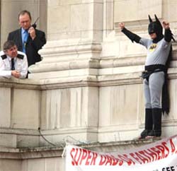 A police officer, left, watches a protester dressed as Batman