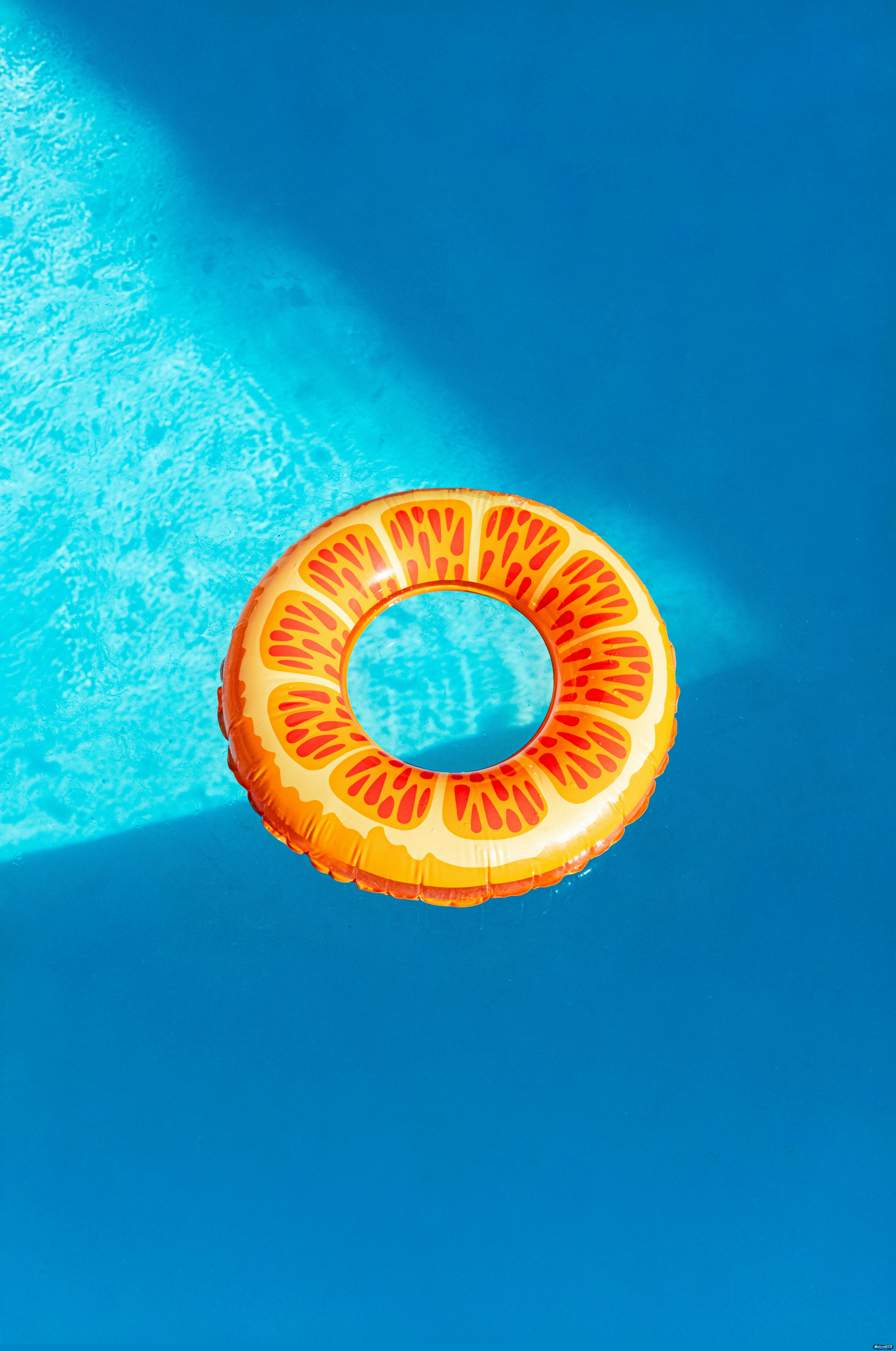 Orange slice inflatable float in a blue swimming pool by Andrew A