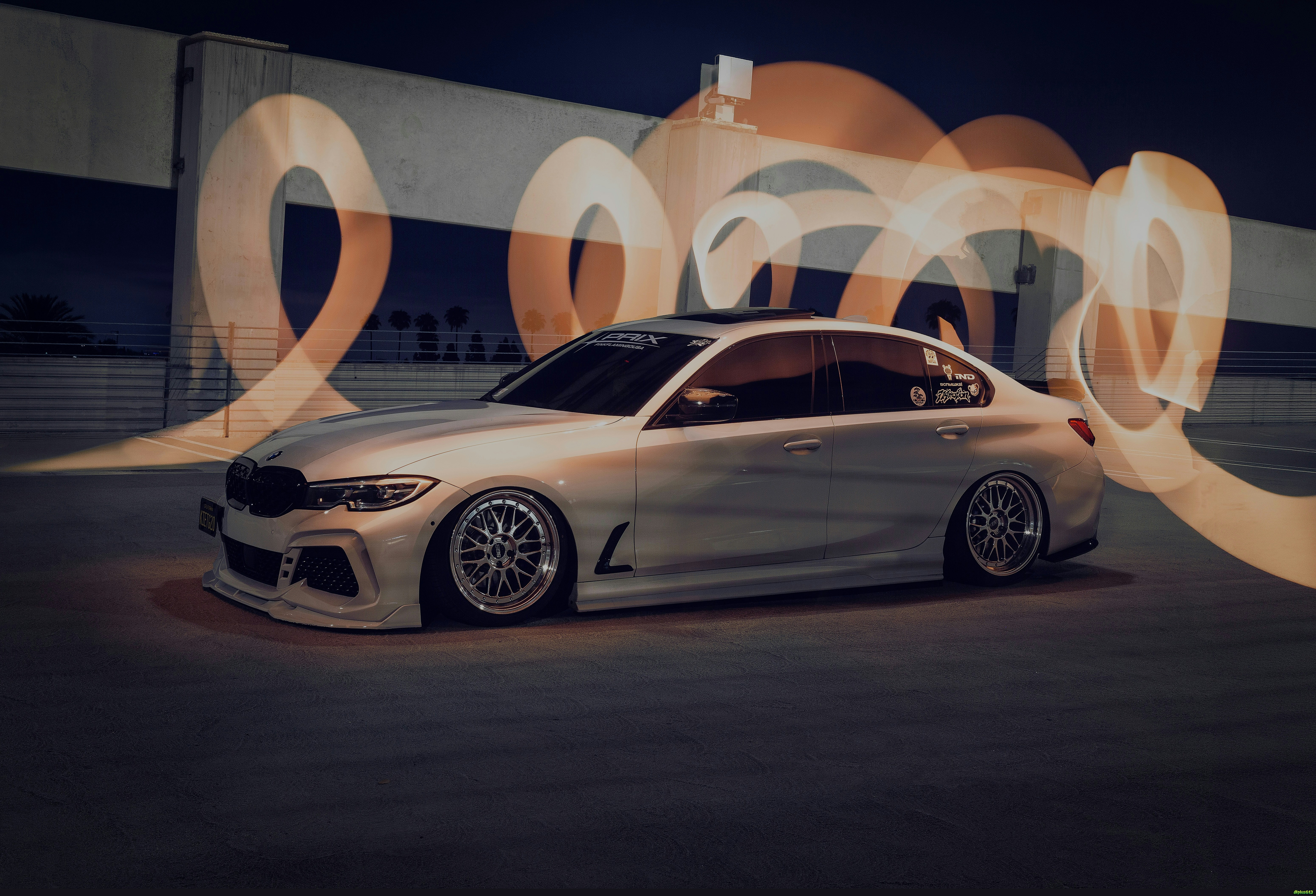 White sedan with light trails forming the number 2023 by Andy Illarionov