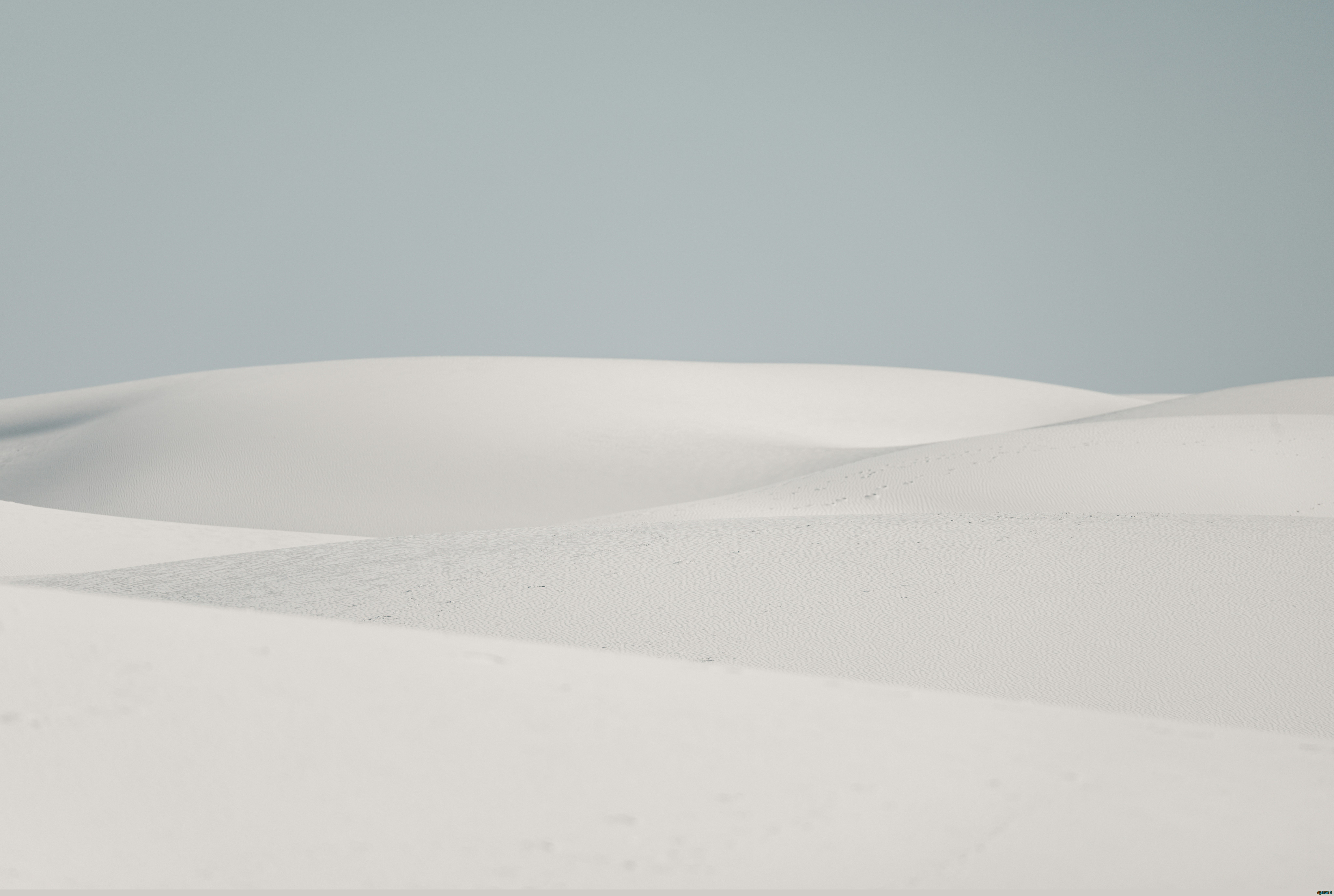 Soft white sand dunes under a pale sky by Royce Fonseca