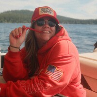 Smiling woman in red hoodie on lake by Karsten Winegeart